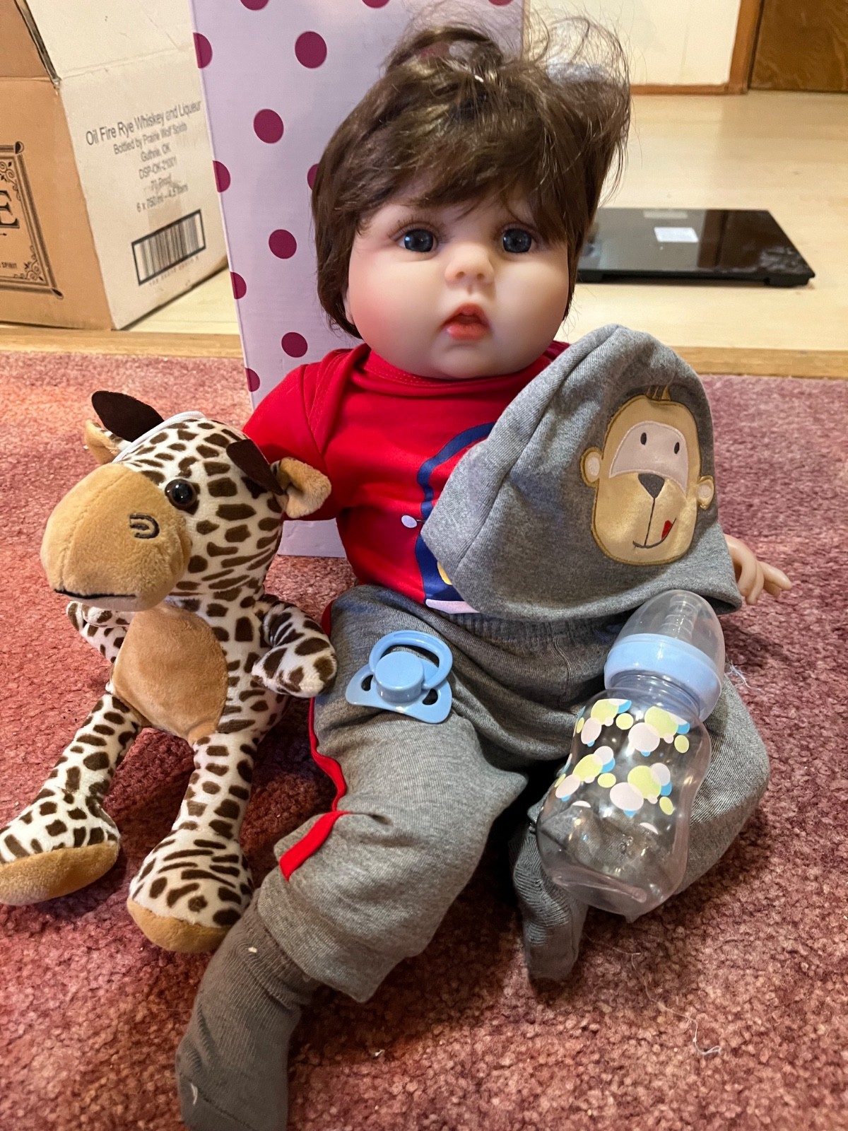 Charex reborn baby boy doll with giraffe, bottle, cap and monkey outfit.