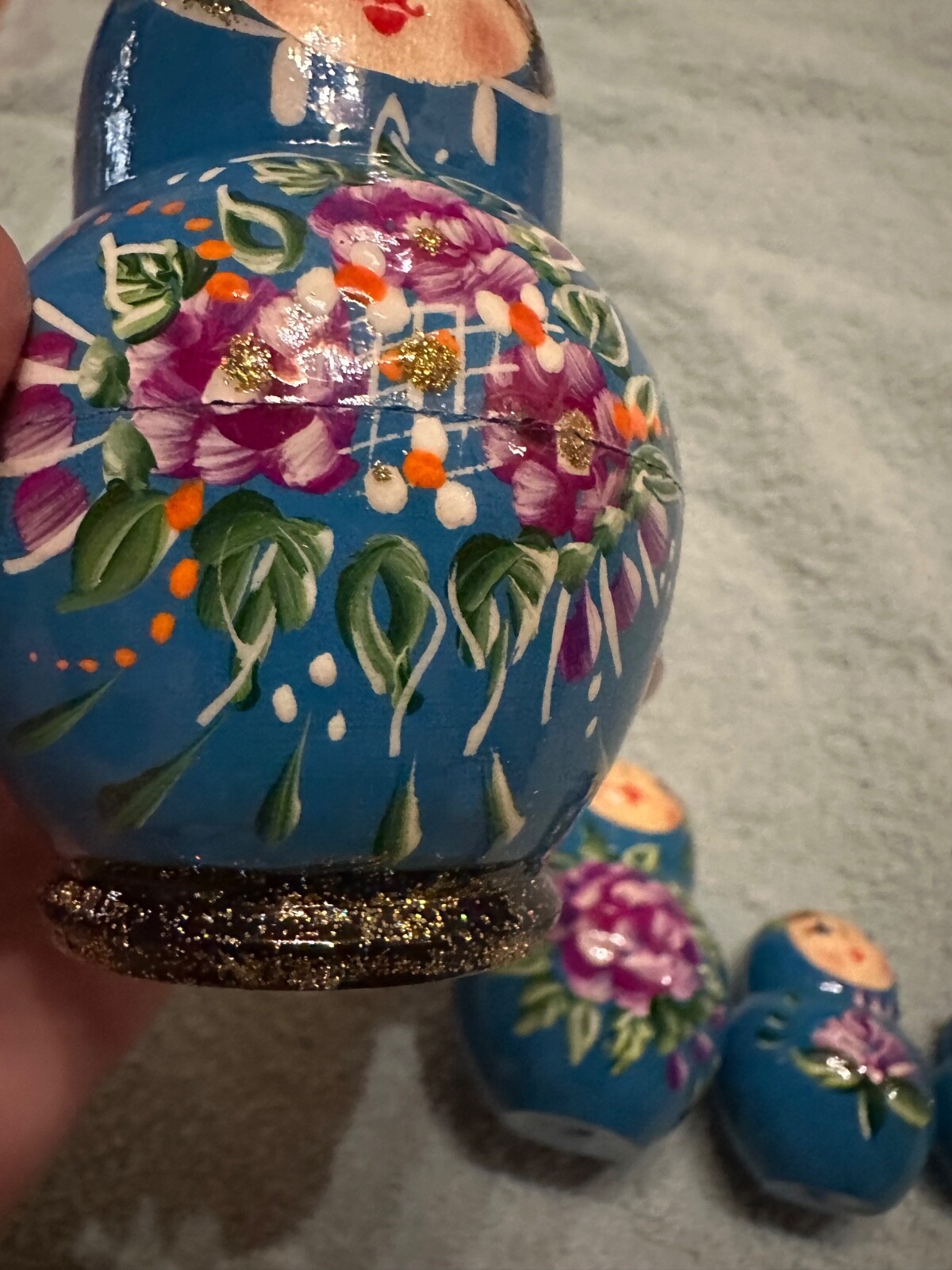 blue nesting doll with green and gold sparkle accents with purple flowers