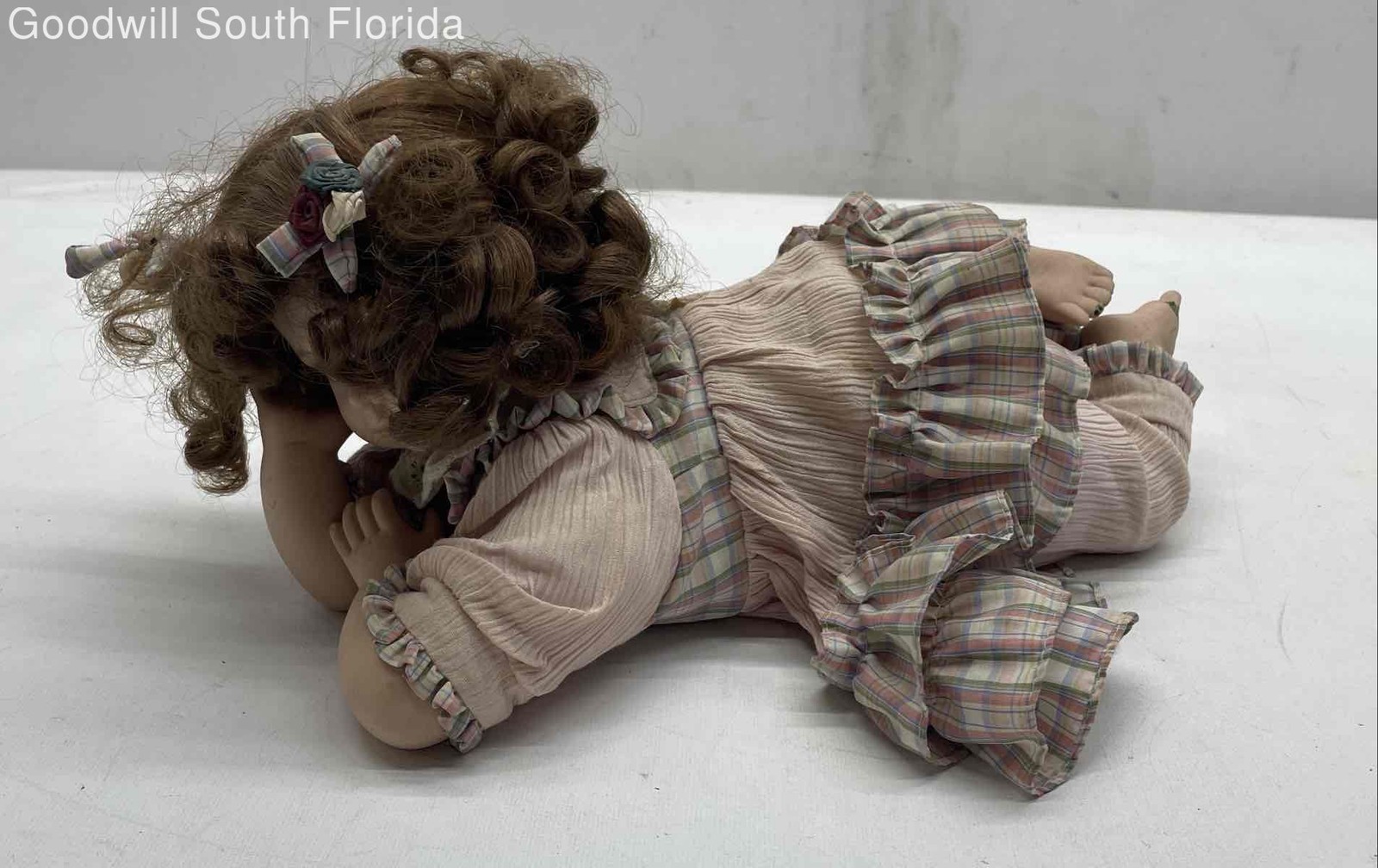 Brown Curly Hair And Blue Eyes Laying Down Girl Porcelain Doll In Pink Dress