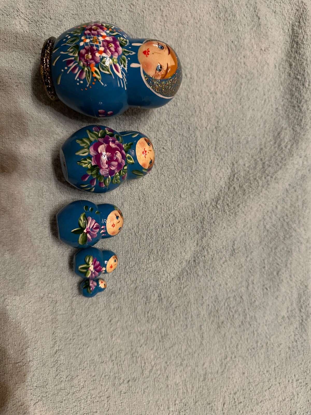 blue nesting doll with green and gold sparkle accents with purple flowers