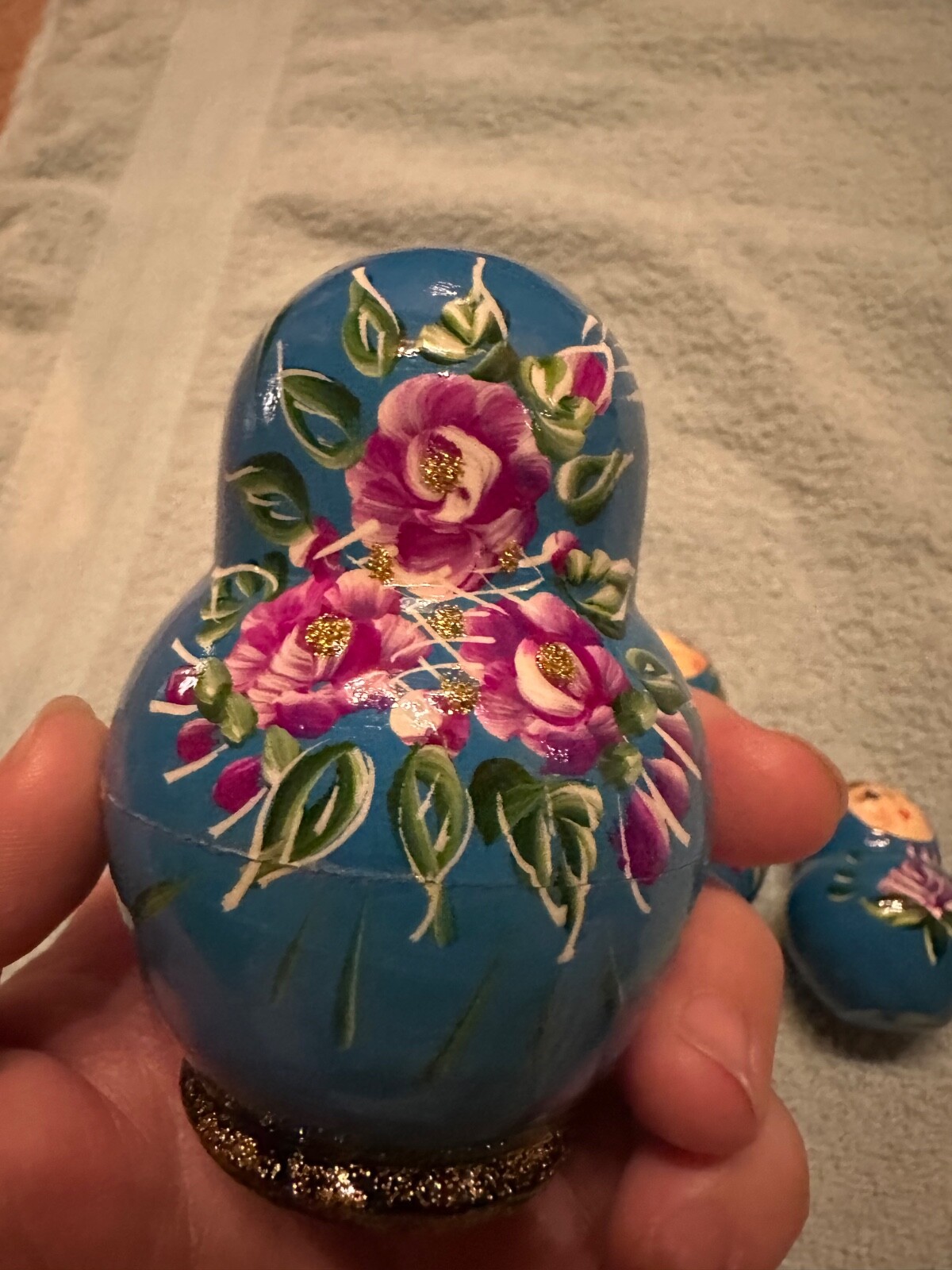 blue nesting doll with green and gold sparkle accents with purple flowers