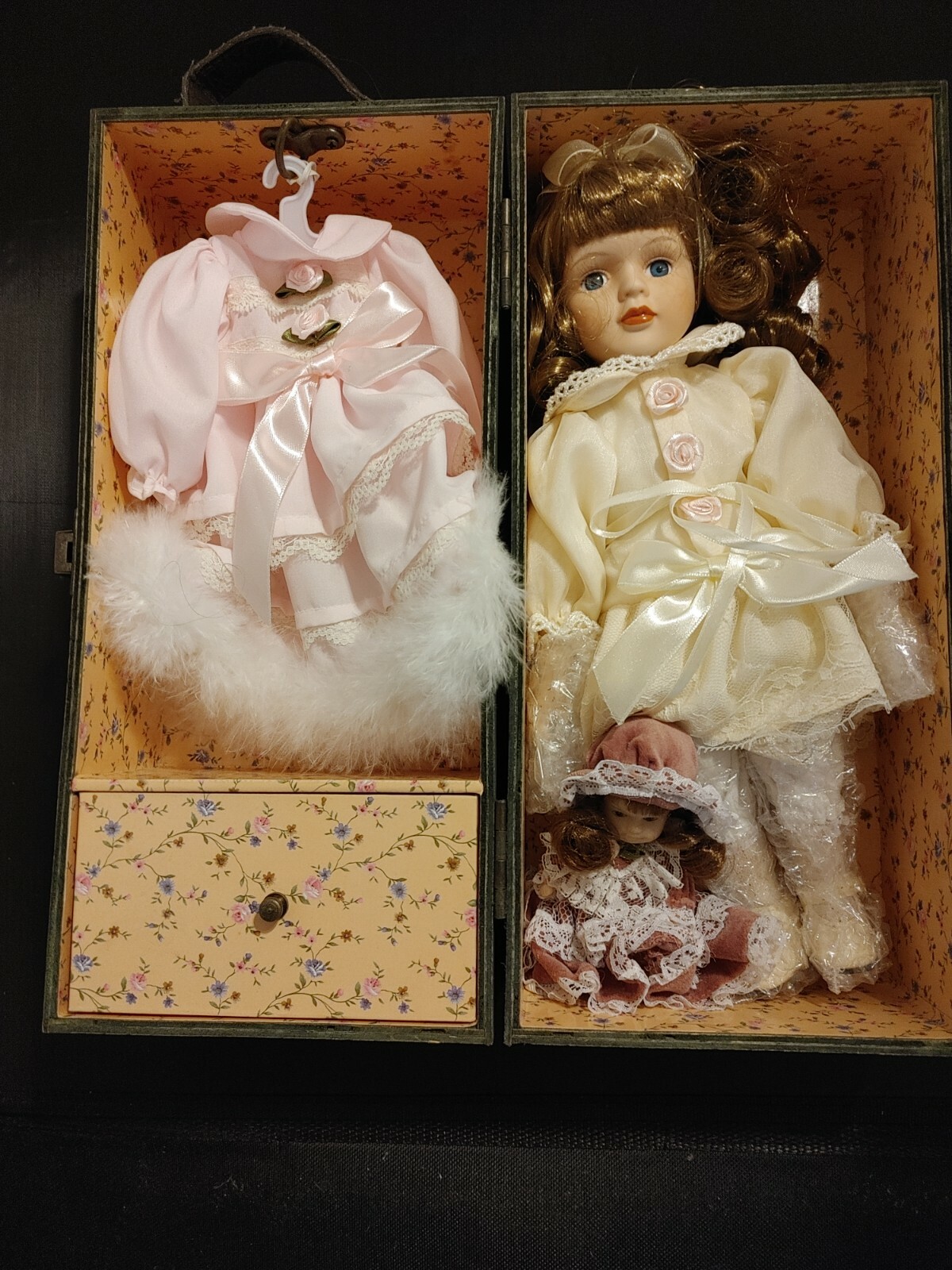 Two dolls in a chest with extra dress