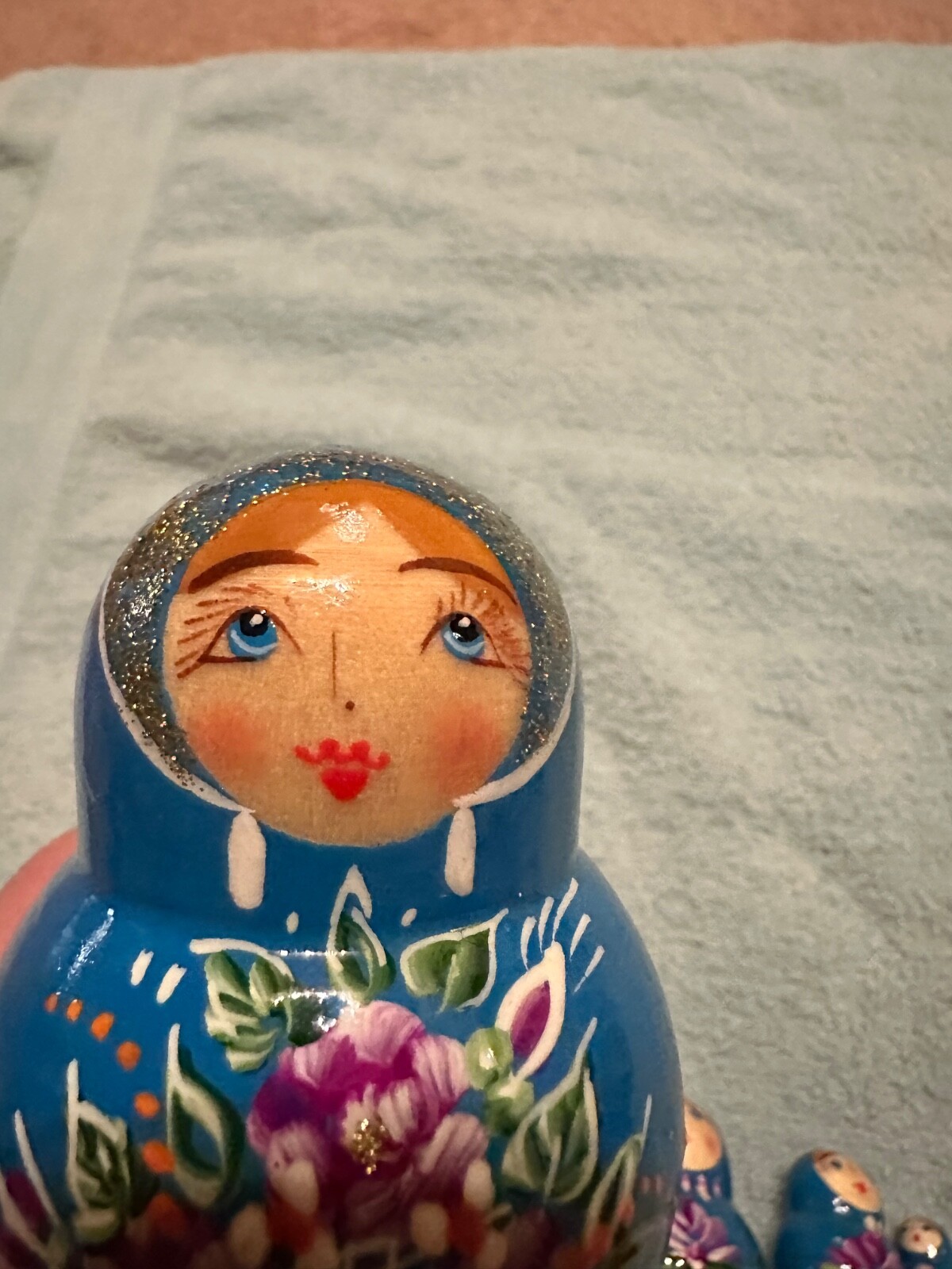 blue nesting doll with green and gold sparkle accents with purple flowers